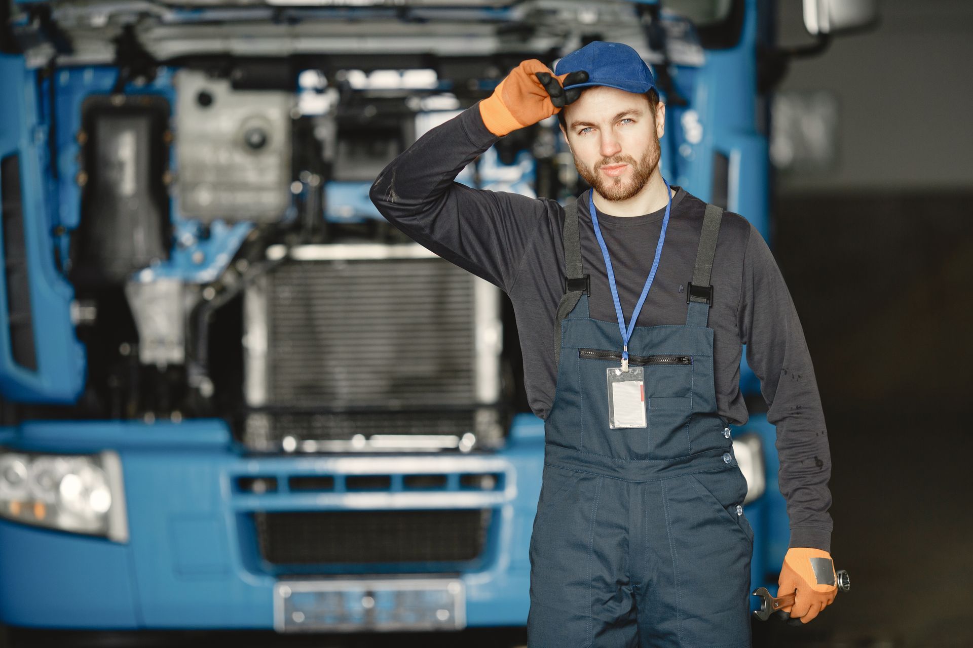 A technician in uniform standing in front of a truck in a workshop