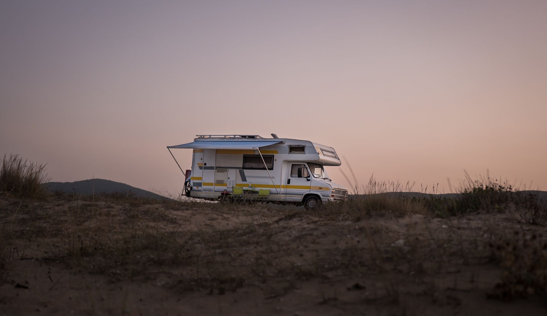A motorhome parked in open country at sunset
