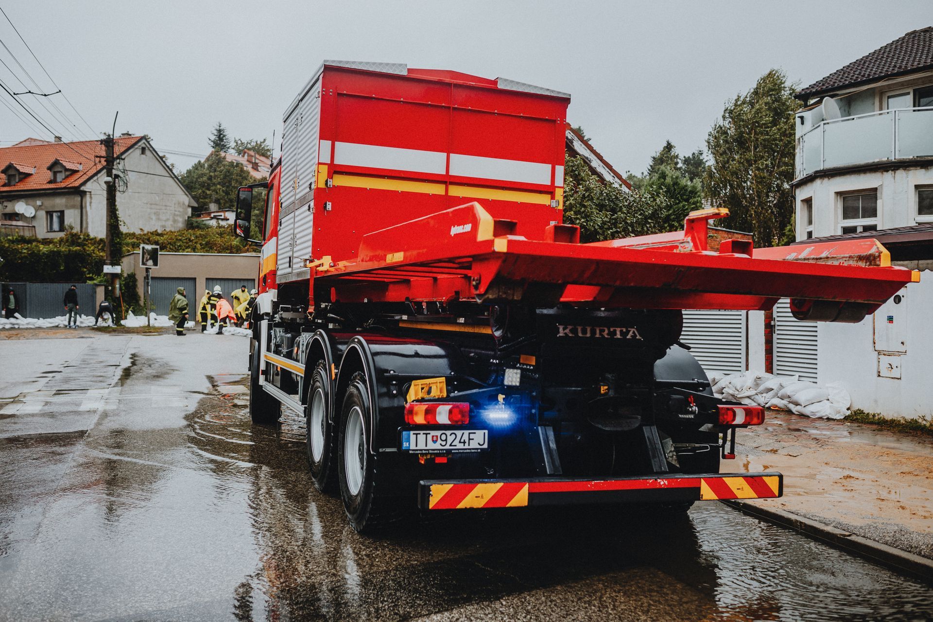 A service truck stopped at the curbside with an operator working beside it