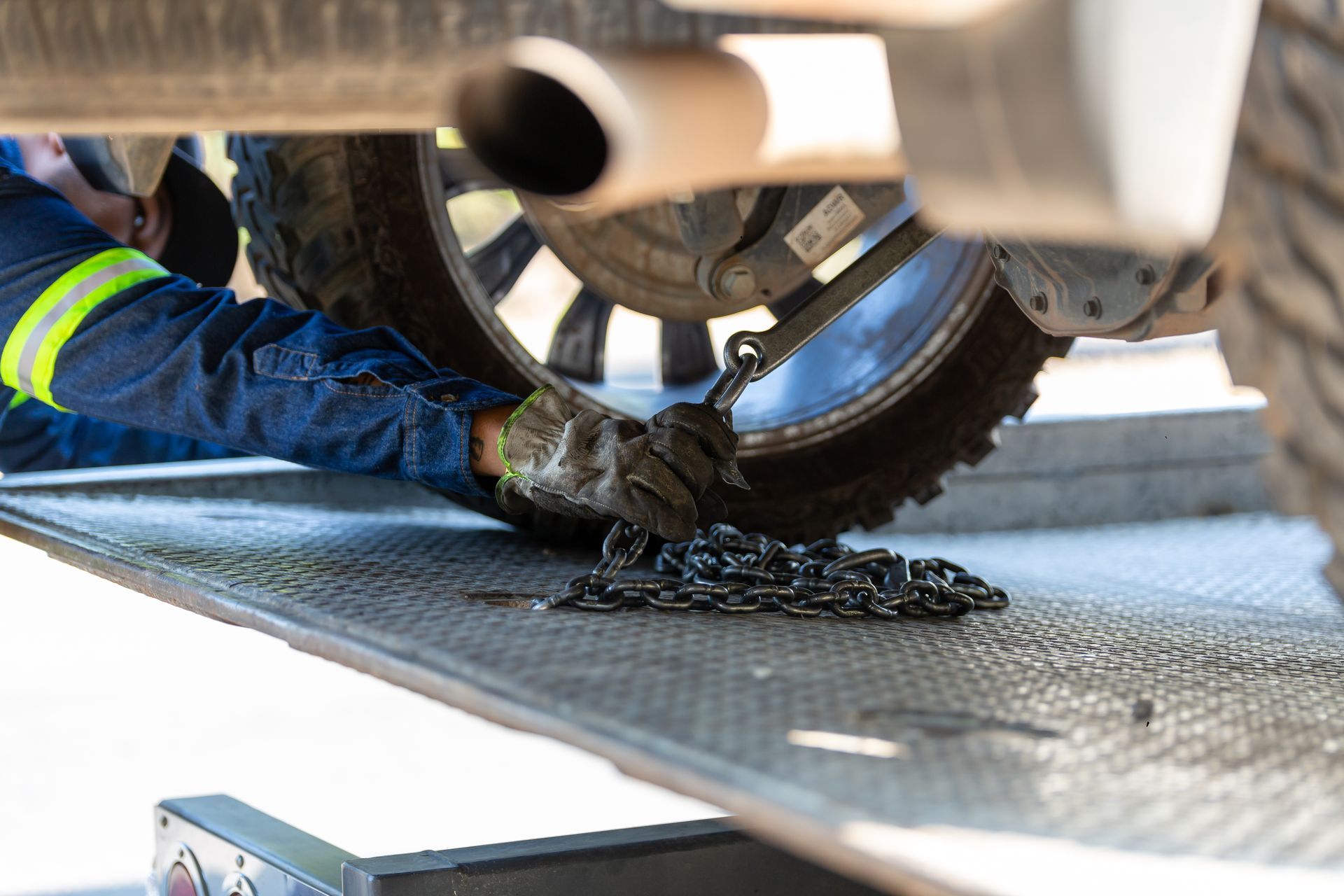 A recovery operator securing a vehicle to a tow deck with a chain
